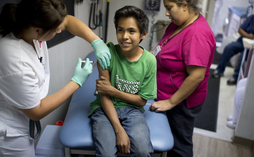 Julio Valenzuela, 11, smiles as he's vaccinated against measles, mumps and rubella at a free clinic in Lynwood, Calif., last August.