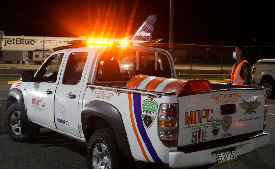 Police stand outside the Las Americas International Airport where a private jet crashed on Wednesday, killing all nine people on board, including Puerto Rican music producer Flow La Movie.