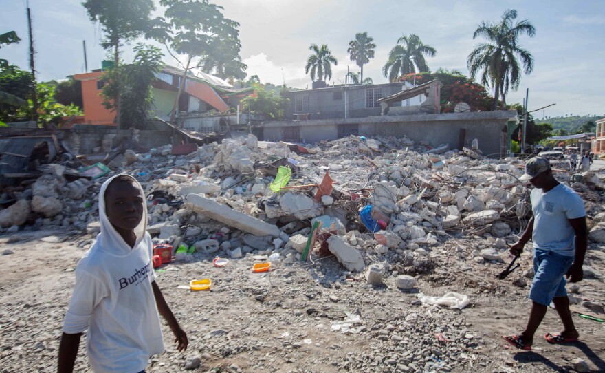 <strong data-stringify-type="bold">Mon., Aug. 16: </strong>Men walk among the debris of a collapsed building in Corvalion, Les Cayes, Haiti.