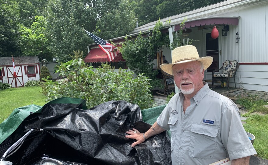 Charlie Smith, 80, pulls back the tarp cover on his motorcycle at his mobile home in Plainville, MA. He was a local selectman and has lived in the town for 41 years. He retired to the Brookside Village park there in 2013.