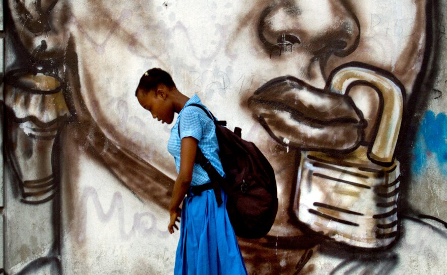 A student at a girl's school in Port-au-Prince walks past a mural by a famous Haitian street artist.