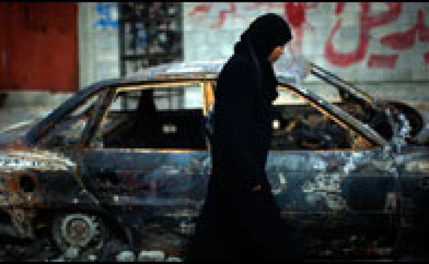 A Palestinian woman walks past a burned car in northern Gaza, Jan. 19. While tensions remain high, a cease-fire between Israeli soldiers and Hamas is still holding.