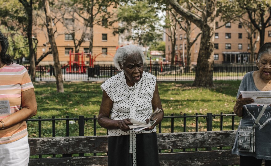 Margarita Barada (center) reads a passage during a service in a park across from the church of Our Lady Queen of Angels in New York City on Aug. 30.