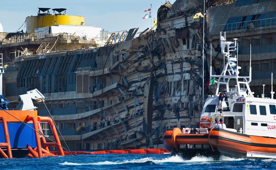 A Coast Guard patrols in front of the severely damaged right side of the Costa Concordia cruise ship after it was righted last week.