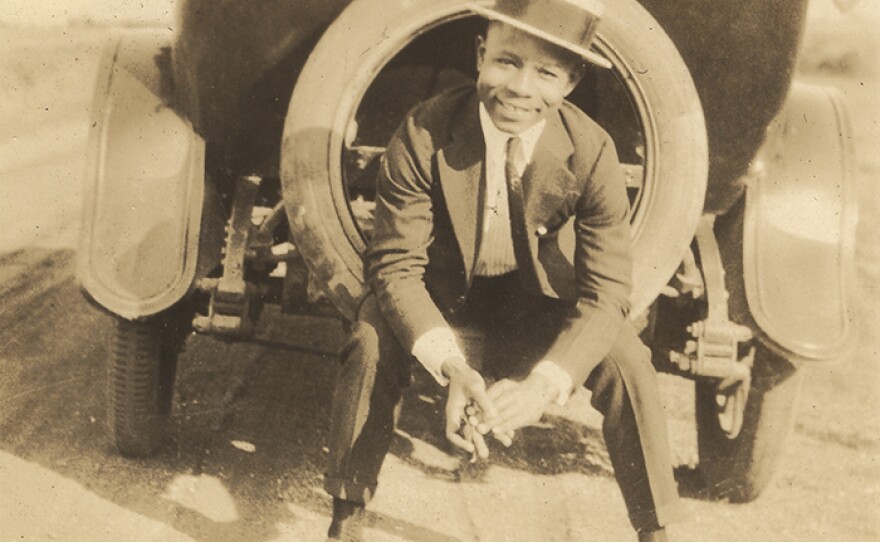 Young African American man sitting in the spare tire on the back of an automobile. (undated photo)