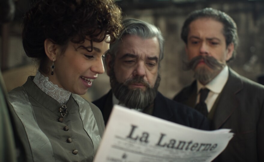 Claire Eiffel, Gustave Eiffel and his associate are reading a newspaper.
