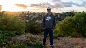 Encanto resident Rob Campbell stands in his backyard on Tuesday, Oct. 29, 2024. Behind him, radio towers mark the site of a future housing development in Emerald Hills.
