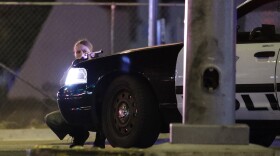 A police officer takes cover behind a police vehicle during a shooting near the Mandalay Bay resort and casino on the Las Vegas Strip, Sunday, Oct. 1, 2017. 