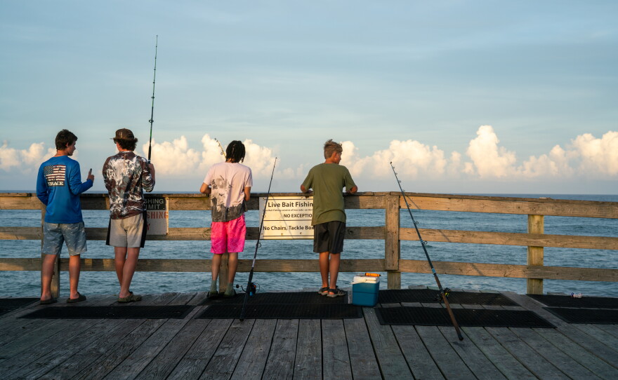 People fish off the pier in Avon, North Carolina.