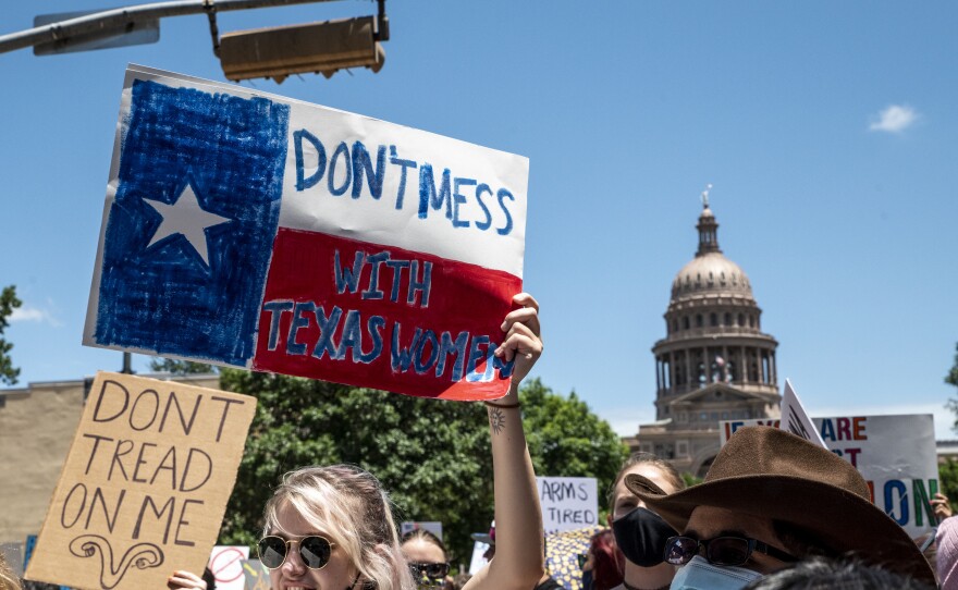 Protesters hold signs as they march in opposition to the anti-abortion law S.B. 8 outside the Texas state capitol on May 29, 2021 in Austin.