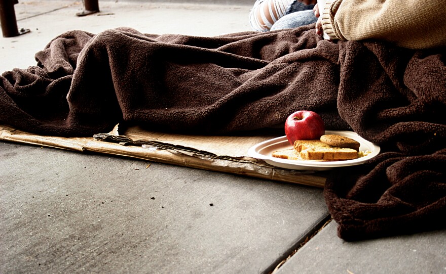 Susan Davis sits on layers of cardboard on a sidewalk in the City Heights neighborhood of San Diego in 2014.