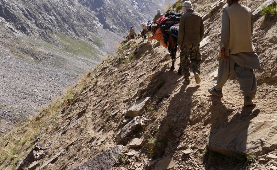 Porters and others navigate the steep descent from the mountains near the base camp, post-expedition.