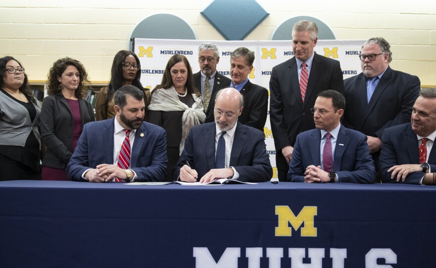 Pennsylvania Gov. Tom Wolf, center, signs legislation overhauling the state's child sex abuse laws.