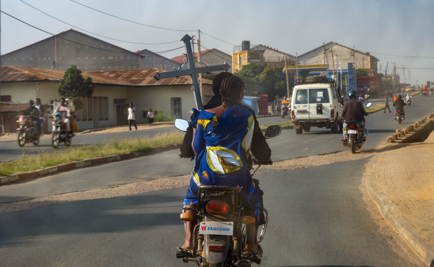 A woman carrying a funeral cross rides on a motorcycle taxi through Bunia, the capital of Ituri province, in the Democratic Republic of Congo, on June 18. Funeral processions and other signs of mourning have become increasingly common as eastern Congo battles an Ebola outbreak.