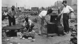 Residents of a Manhattan Hooverville preparing food in a mobile drum, in a photo from 1932.