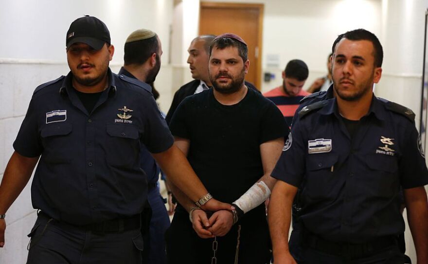 Israeli Yosef Haim Ben-David (center), the ringleader in the killing of Palestinian teenager Mohammed Abu Khdeir in 2014, is escorted by Israeli policemen at the district court in Jerusalem on Tuesday.