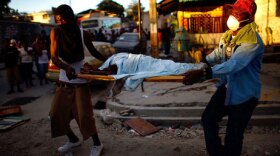 Haitian men carry the body of a child to a dump truck near downtown Port-au-Prince on Thursday, January 14, 2010. Tuesday's earthquake has left the Haitian capital devastated with thousands dead and hundreds of thousands homeless.