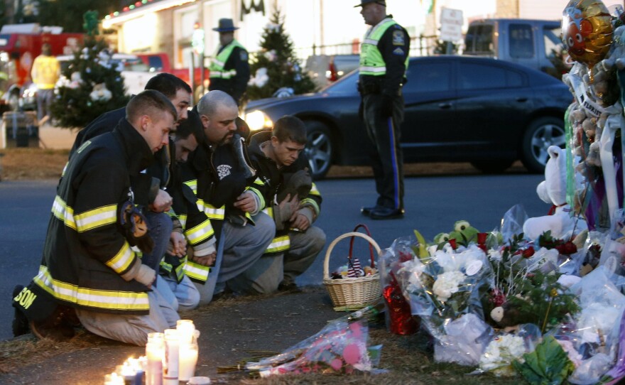 Firefighters pay their respects at a memorial for shooting victims near Sandy Hook Elementary School on Saturday.