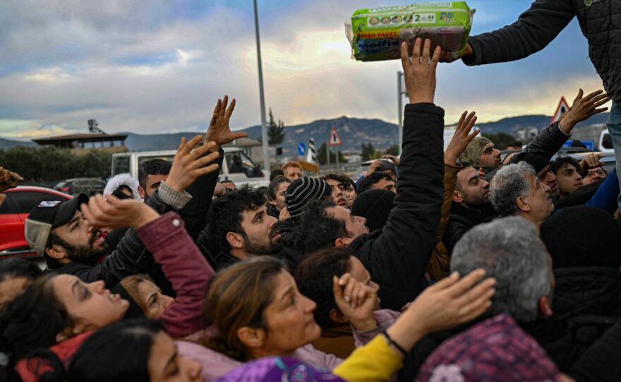 Earthquake survivors gather to collect supplies at a diaper distribution in Hatay, Turkey, on Tuesday, a day after a 7.8 magnitude earthquake struck the country's southeast.