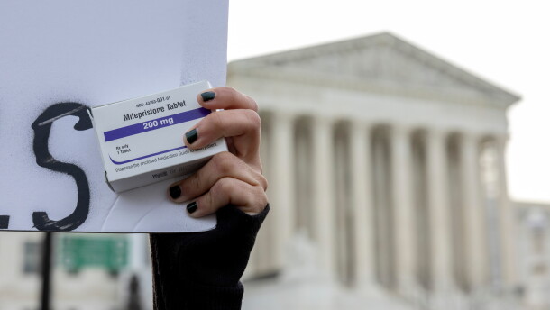 An abortion-rights activist holds a box of mifepristone pills as demonstrators from both anti-abortion and abortion-rights groups rally outside the Supreme Court on March 26, 2024.