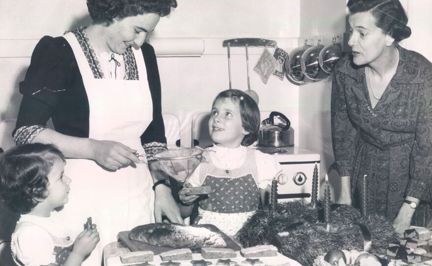 During advent, many Germans bake Christmas cookies and breads. In 1959, Mrs. Otto Soltmann, right, kept the custom going with her children and their cook, left, Miss Edith Mallmann.