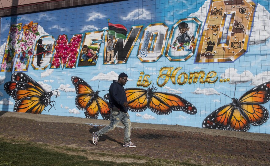 William Allen walks by a mural in the Homewood neighborhood of Pittsburgh.