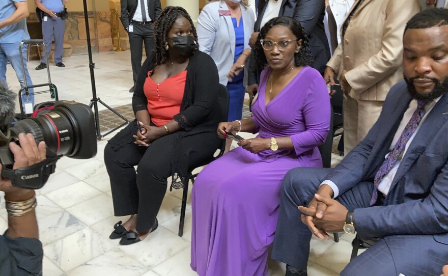 Relatives of Ahmaud Arbery including his sister Jasmine Arbery, left, and his mother Wanda Cooper-Jones, second from left, sit at the Georgia state capitol in Atlanta on Monday to witness Gov. Brian Kemp sign a law repealing citizen's arrest in Georgia.