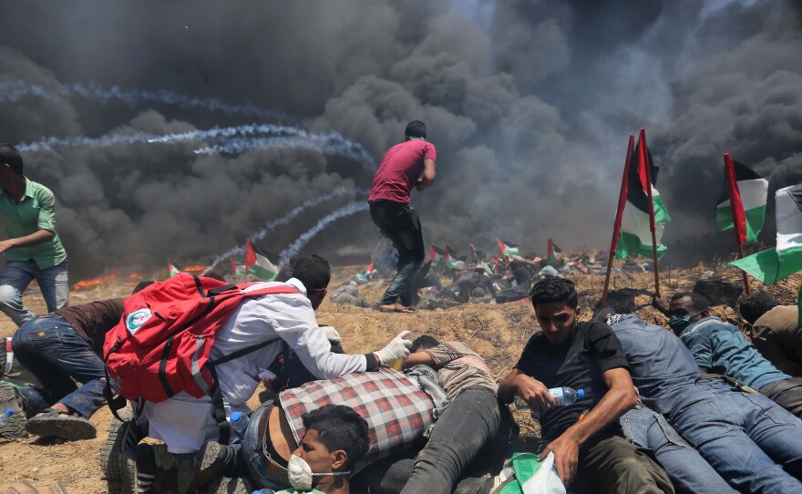 Palestinians set tires on fire, as Israeli soldiers attempt to prevent protesters from breaking through the Gaza-Israel border. The demonstration marked the 70th anniversary of Nakba, or catastrophe, a commemoration of the displacement of hundreds of thousands of Palestinians in the war surrounding Israel's creation.