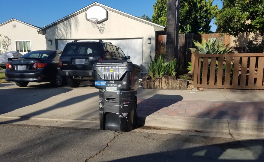 A damaged city of San Diego trash bin sits in front of a house in September 2019.