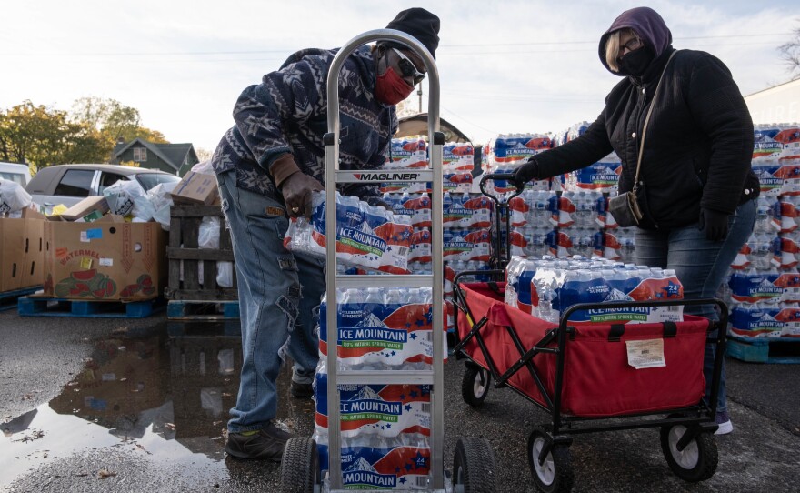 Volunteers help distribute cases of water bottles at Asbury United Methodist Help Center in Flint on Oct. 20, 2020. Authorities say Flint's water now meets federal safety guidelines, but many residents remain unconvinced.