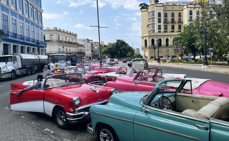 Classic 1950s-era cars sit idling on Havana's Paseo del Prado. On a recent day, driver Eduardo Cedeño said he hadn't had a single rider in his shiny red 1956 Buick convertible.