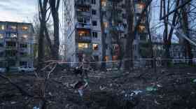 A woman with a dog walks among the rubble of a house damaged after a Russian strike on residential area in Kyiv, Ukraine, on Thursday, April 16, 2026.