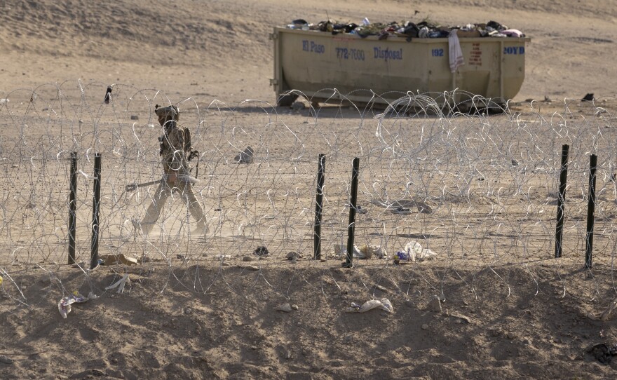 Texas National Guard soldier walks through an emptied-out migrant camp at the U.S.-Mexico border.