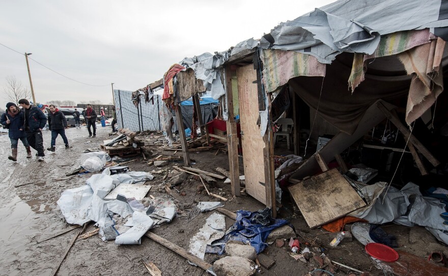 People walk in the southern part of the so-called "Jungle" migrant camp in Calais, northern France, which is being dismantled, on March 10, 2016.