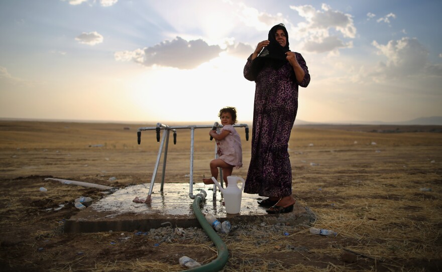 A women and a girl wash at a camp in Kalak set up for those fleeing the fighting in northern Iraq. The escalating conflict has sent shock waves across the region and is further destabilizing the Middle East.