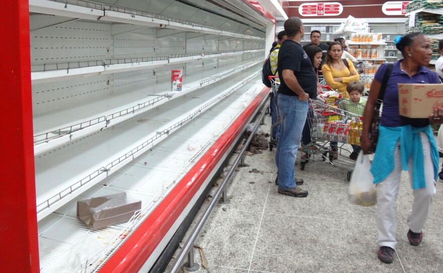 Empty shelves, like these at a supermarket in Caracas, are a common sight in Venezuela. People can shop only on designated days at government-run stores. They're limited in what they can buy and must undergo fingerprint scanning to prove their identity.