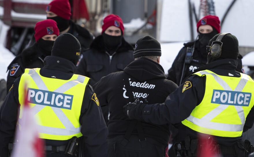 A man is led away after leaving his truck on Friday as police make arrests to end the ongoing protest in Ottawa.