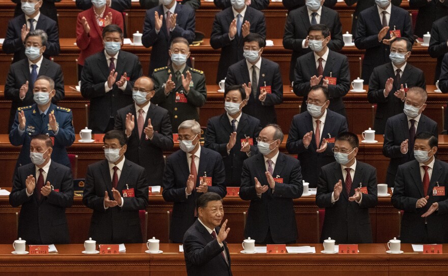 Chinese President Xi Jinping, right, is applauded as he waves to senior members of the government.