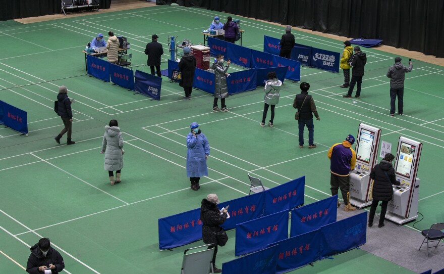 People wait in line to see health workers at a temporary fever clinic set up by a hospital to treat potential COVID-19 patients in a sports center on Dec. 18, 2022 in Beijing. COVID cases have surged since the government scaled back its 'zero-COVID' policies.