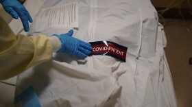 In this Jan. 9, 2021, file photo, a hospital worker places a "COVID Patient" sticker on a body bag holding a deceased patient at Providence Holy Cross Medical Center in the Mission Hills section of Los Angeles. 