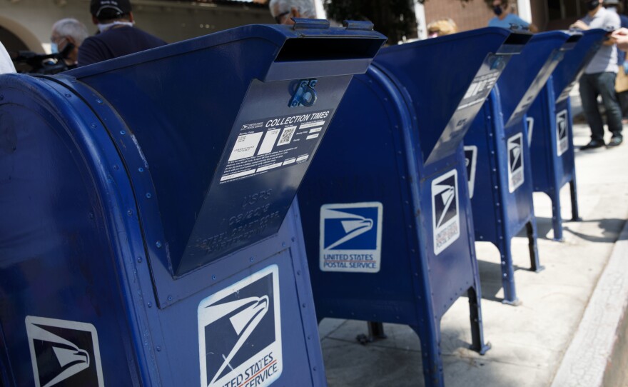 A customer deposits mail into a U.S. Postal Service mail collection box this week in Burbank, Calif.