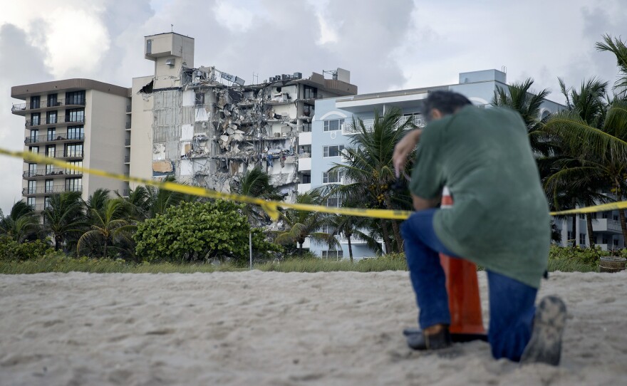 A man prays near where search and rescue operations are ongoing at the site of the partially collapsed 12-story Champlain Towers South condo building in Surfside, Fla.