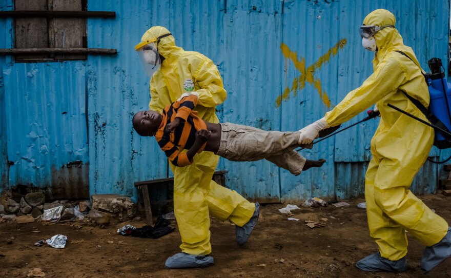 James Dorbor, age 8, was suspected of having Ebola. Medical staff in protective gear carried him into a treatment center on September 5, 2014, in Monrovia, Liberia.