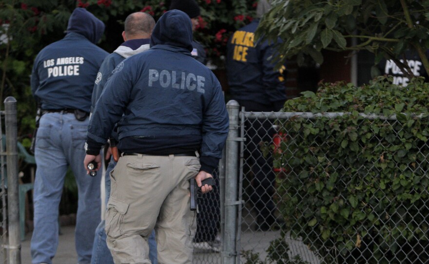 U.S. Immigration and Customs Enforcement officers and Los Angeles police officers enter a house during a joint operation in 2009.