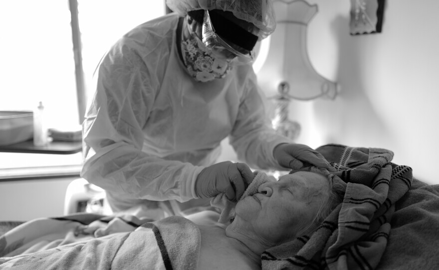 Delores Jetton carefully bathes Elvy Kaik during a hospice visit on April 23, 2020. Because their work is so hands-on, Delores and other home health care workers on Whidbey Island wear extensive gear and take extra precautions to minimize COVID risk.
