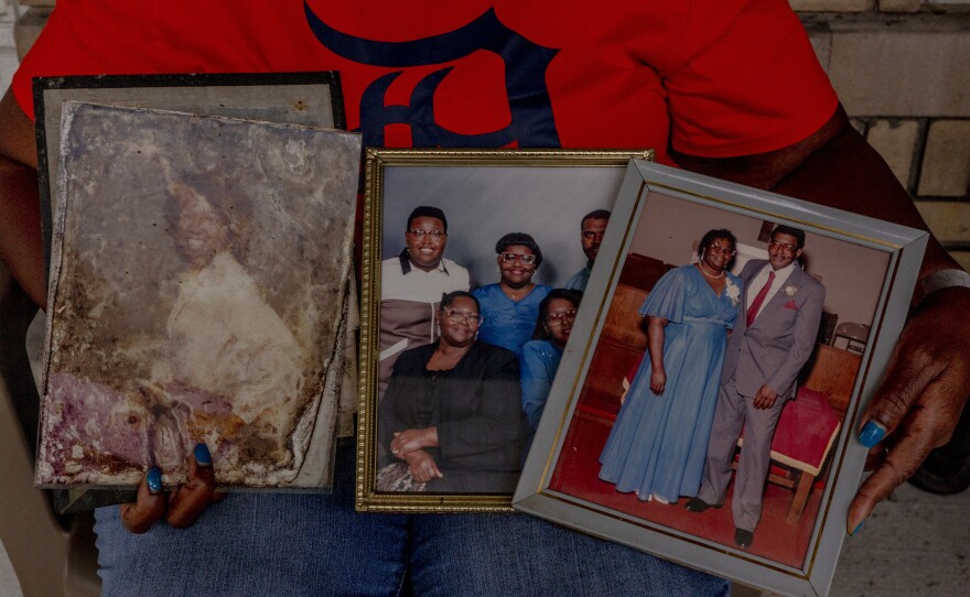 Bonham holds family photos she saved from her basement that was flooded with three feet of water.