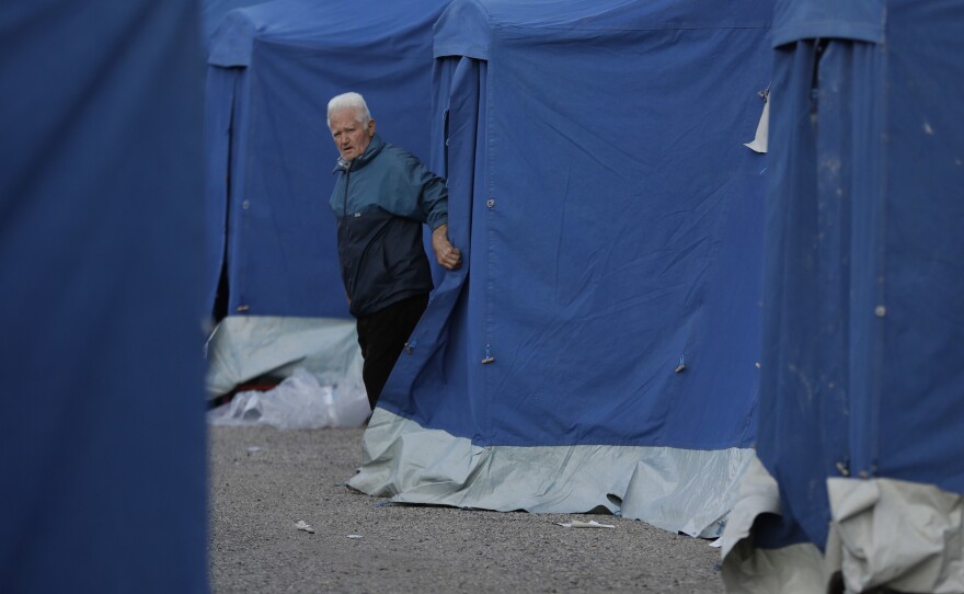 A man walks out of a tent in a camp near Pescara del Tronto, Italy, on Thursday. Italy's civil protection agency set up tent cities around the towns affected by Wednesday's powerful earthquake to accommodate the homeless.