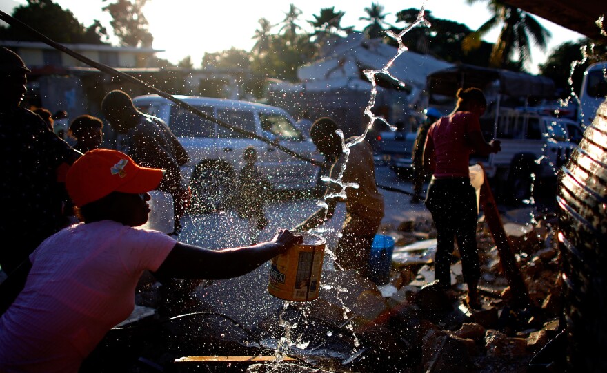 People gather around broken water pipes to collect drinking water in Port au Prince, Haiti, after the January 2010 earthquake.