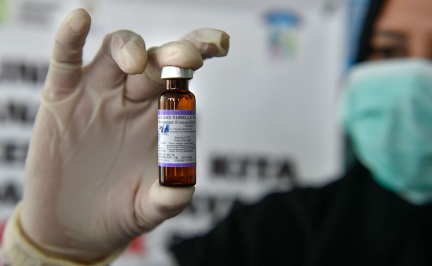 A medical worker holds a measles-rubella vaccine at a health station in Banda Aceh, Indonesia.