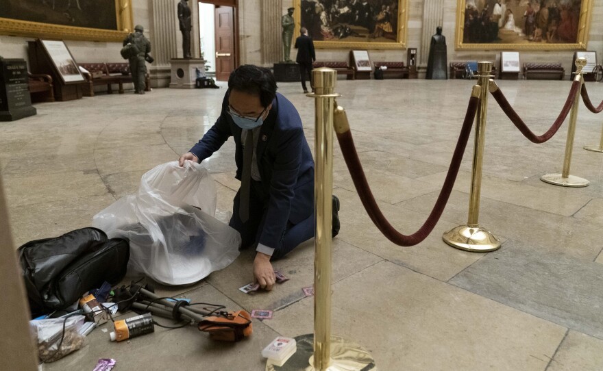 Rep. Andy Kim, D-N.J., cleans up debris and personal belongings strewn across the floor of the Rotunda in the early morning hours of Thursday, Jan. 7, 2021, after protesters stormed the Capitol in Washington, on Wednesday. (AP Photo/Andrew Harnik)